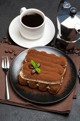 Classic tiramisu dessert on ceramic plate, milk or cream and cup of coffee on concrete background