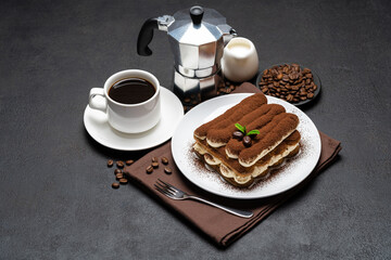 Classic tiramisu dessert on ceramic plate, milk or cream and cup of coffee on concrete background