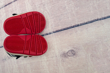 red sole of children's shoes on a wooden background. Copy of space