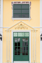 Fototapeta premium The green retro house door on the yellow wall.With beautiful patterns.With a window on top