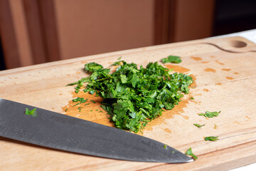 Sliced parsley on a wooden Board next to a knife in the kitchen