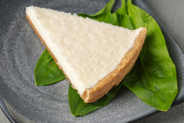 Vegetarian cheesecake on a gray plate with green leaves close-up