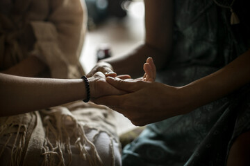 A woman supports and takes care of another woman. Hand massage in a dark relaxing room. Close up of a hand of a woman. Image with selective focus, noise effect and toning.