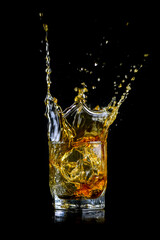 Splashing of whiskey out of glass isolated on black