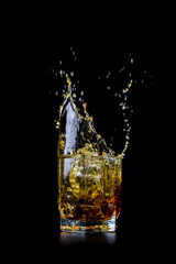 Splashing of whiskey out of glass isolated on black