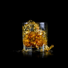 Splashing of whiskey out of glass isolated on black