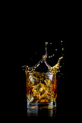 Splashing of whiskey out of glass isolated on black