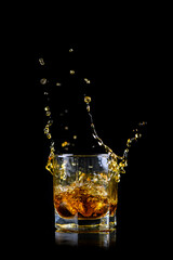 Splashing of whiskey out of glass isolated on black