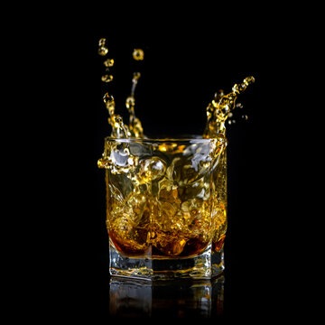 Splashing of whiskey out of glass isolated on black