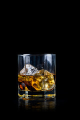 Glass of whiskey with cube ice on black background