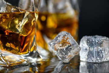 Glass of whiskey with cube ice on black background
