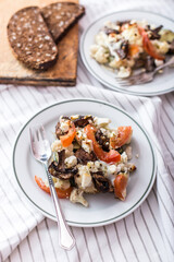 Plates of baked vegetables with feta cheese on a light tablecloth background
