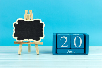 wooden calendar with the date of June 20 and an easel on a blue background, place for text, World Zoo Elephants Day, World Refugee Day, Summer Solstice