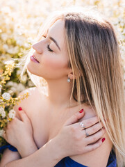 Sensual calm portrait of beautiful hipster woman in blooming bush with white flowers of spirea. Copy space. Stylish blonde woman in blue dress in garden