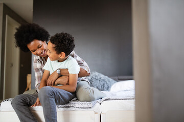 Happy mother playing, having fun, hugging with her son at home