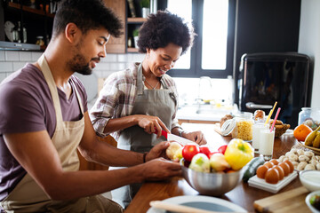 Beautiful young couple having fun and laughing while cooking in kitchen