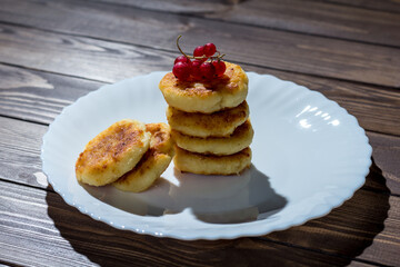 Cottage cheese pancakes or syrniki with redcurrant, icing sugar.
