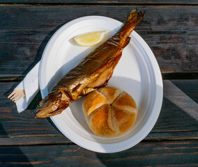 Smoked trout whole with horseradish and garnish. Gourmet grilled salmon fish on a plate. Delicious healthy meal made of fish on a rustic table.