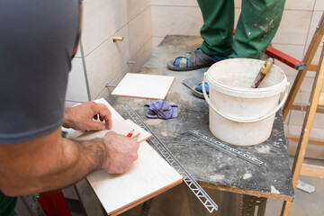 Fototapeta na wymiar A construction worker measures and prepares to cut ceramic tiles