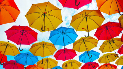Fototapeta na wymiar Colorful umbrellas hanging overhead over a blue sky