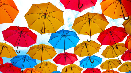 Colorful umbrellas hanging overhead over a blue sky