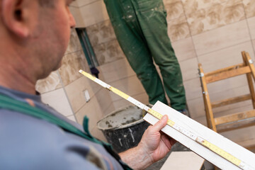 A construction worker measures and prepares to cut ceramic tiles