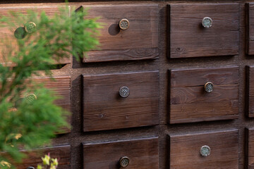 A wooden chest of drawers with small drawers and round brass handles. Simple furnishings