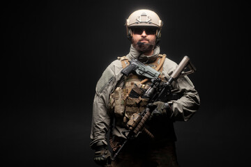 Fototapeta premium USA soldier in a military suit with a rifle against a dark background, an American commando with a gun at night