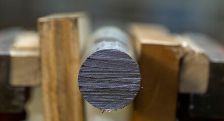 Cut off round stock mild steel clamped in a vise with wood. Shows grain of cut off metal photograph