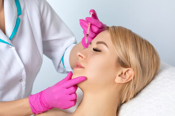 The doctor corrects a small hump on the nose. Plastic surgery, the surgeon makes rhinoplasty of the...