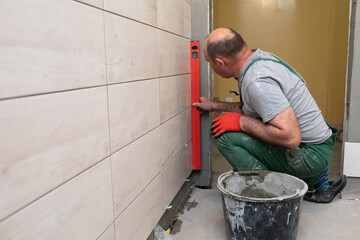 The tiler checks with a spirit level whether freshly laid tiles are evenly aligned with the wall.