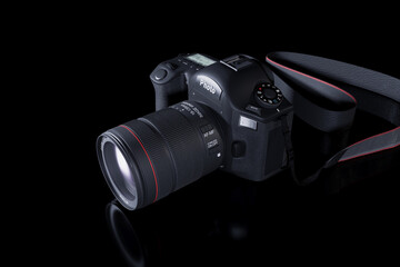 Professional digital camera with a zoom lens and a leather strap on a black background with copy space. View from above. Realistic 3d render. Place for advertising text. Reflection at bottom
