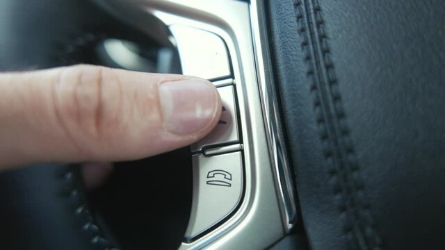 Using the Bluetooth buttons located on the steering wheel of a car to talk over the phone hands-free.