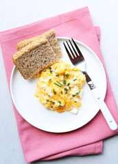 Scrambled eggs on a white plate. Healthy food or breakfast concept.