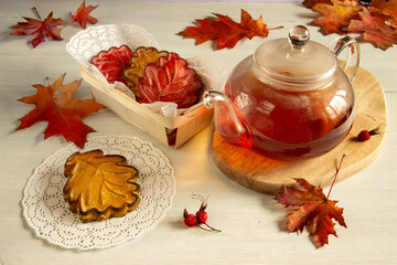 Naklejka na ściany i meble Shortbread in the shape of leaves and a teapot on the table decorated with autumn leaves.