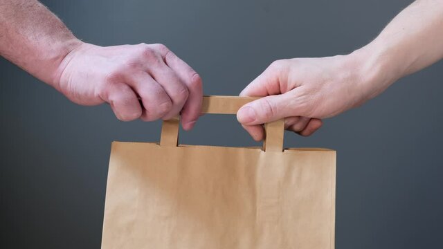Close up hold in hand brown clear empty blank craft paper bag for give takeaway