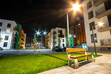 Yard between residential apartment buildings with empty wooden bench and modern flat housing. Real...