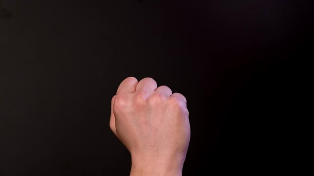 Man shows middle finger on black background. Close up