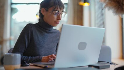 Portrait young woman in eyeglasses using laptop in coworking space or cafe. female sitting in front open laptop computer. Study, learning, remote work, freelance.