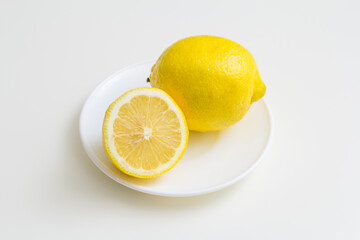 a whole lemon and half a lemon on a plate on a white table