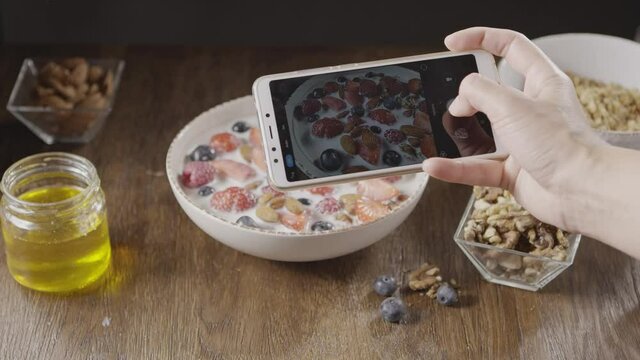 Woman's hand is making photos of freshly cooked healthy breakfas