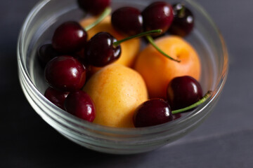 glass bowl of ripe red cherries and apricots