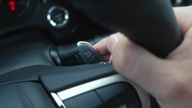 Closeup on a person sitting inside the vehicle and using Paddle Shifters to change gears while driving