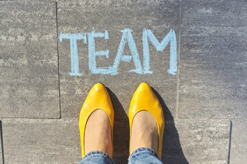 Team concept, top view on woman legs and text written in chalk on gray sidewalk