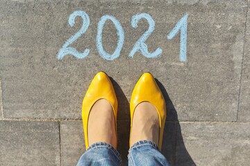 2021 year concept, top view on woman legs and text written in chalk on gray sidewalk