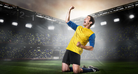 Fototapeta na wymiar Goal scored. Excited soccer or football player is celebrating success on stadium. Happy team sports player kneel on field.