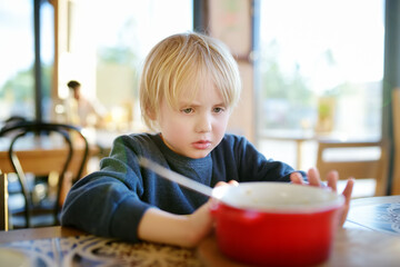 Little boy sitting the table in cafe or restaurant and doesn't want to eat. Healthy food. Kids...