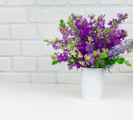 Fototapeta na wymiar Beautiful bouquet of lilac purple flowers in a white vase on a white background. Mothers Day. Greeting card. Place for an inscription.