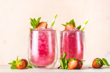 Fresh strawberry cocktail. Fresh summer cocktail with strawberry and ice cubes. Glass of strawberry soda drink on light pink background