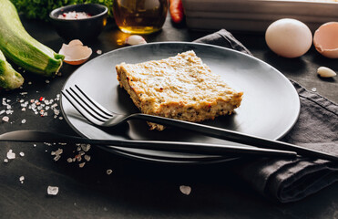 Zucchini casserole on dark background. Dietary, low-calorie, healthy food. Homemade Casserole from squash with chicken and eggs.